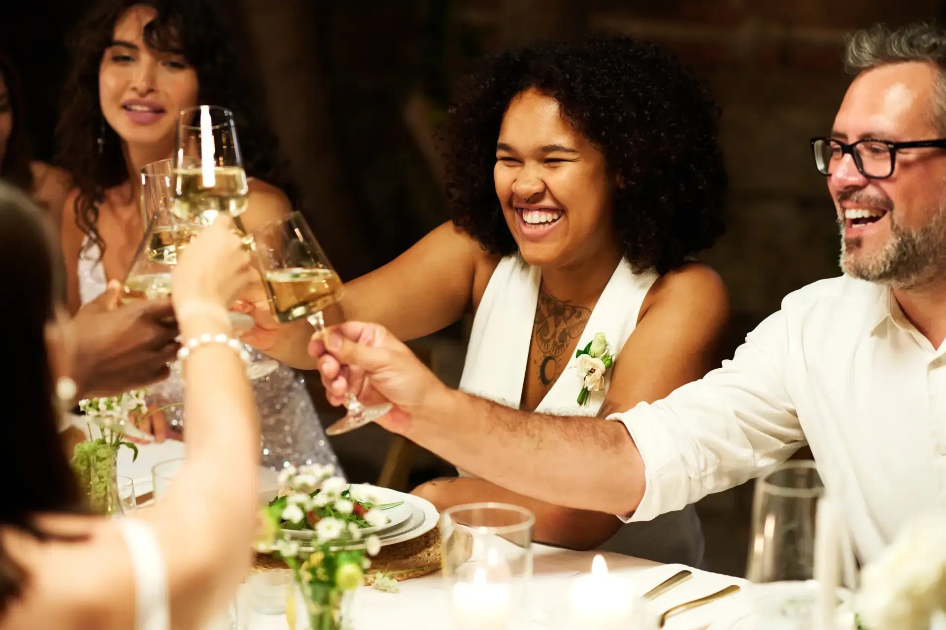 Happy young African American bride in wedding attire toasting with friends