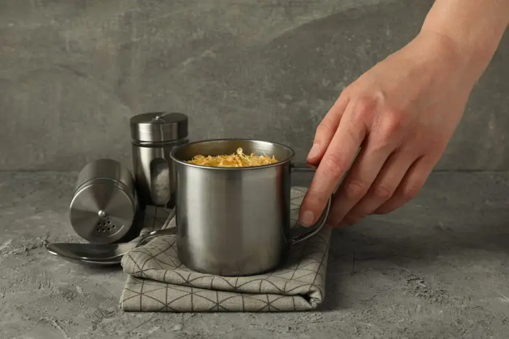 Cheese soup in a metal cup with kitchen utensils